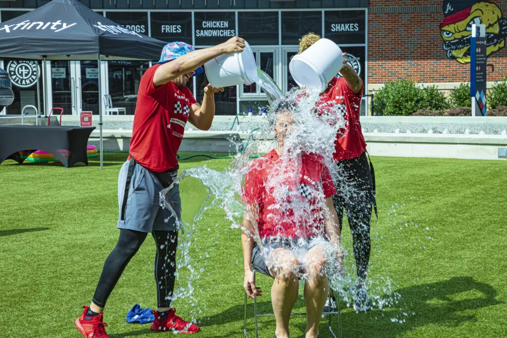 Tracy Pitcher is doused with water by two employees during fundraising challenge