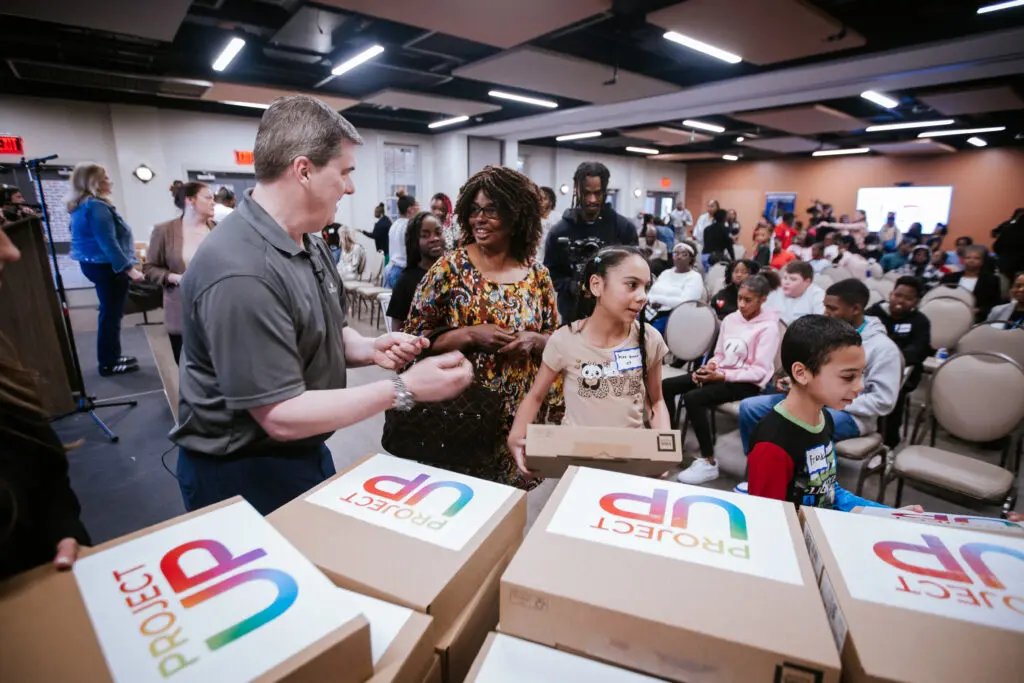 Alt text: Mike McArdle, SVP of Big South Region, helps pass laptops to Boys and Girls Club students.
