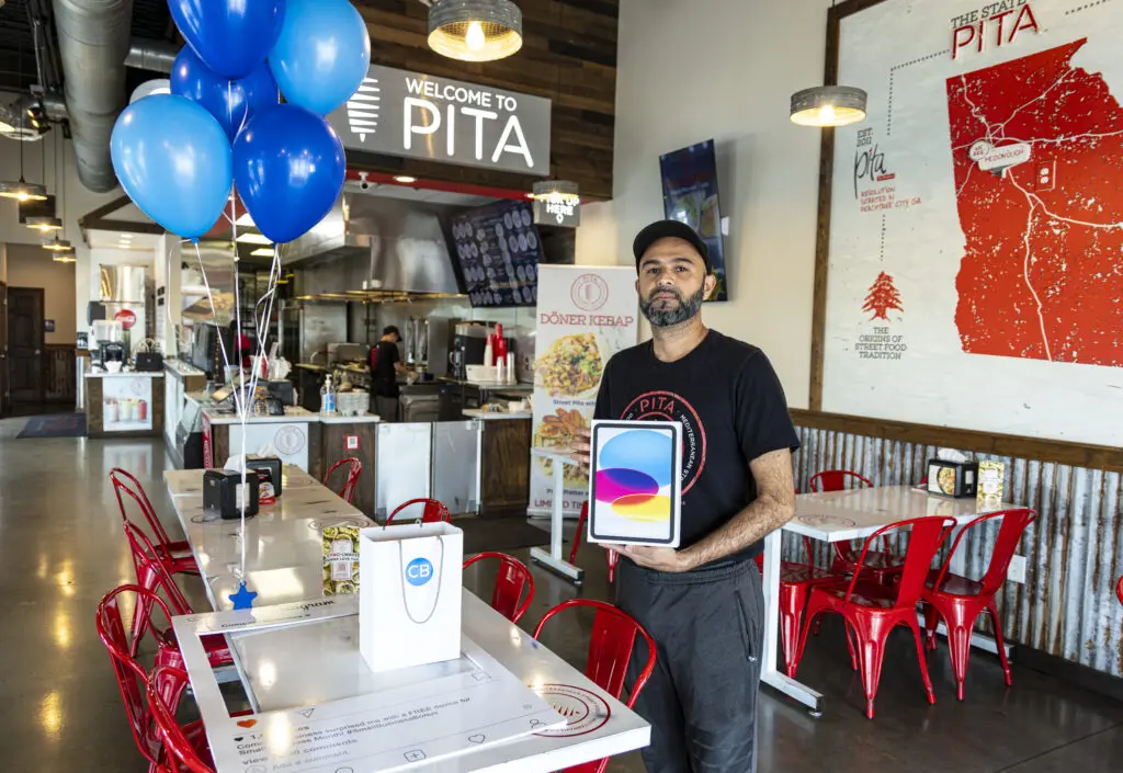 PITA Mediterranean Street Food Owner Abbas Momin holds up an iPad gifted to him from Comcast Business