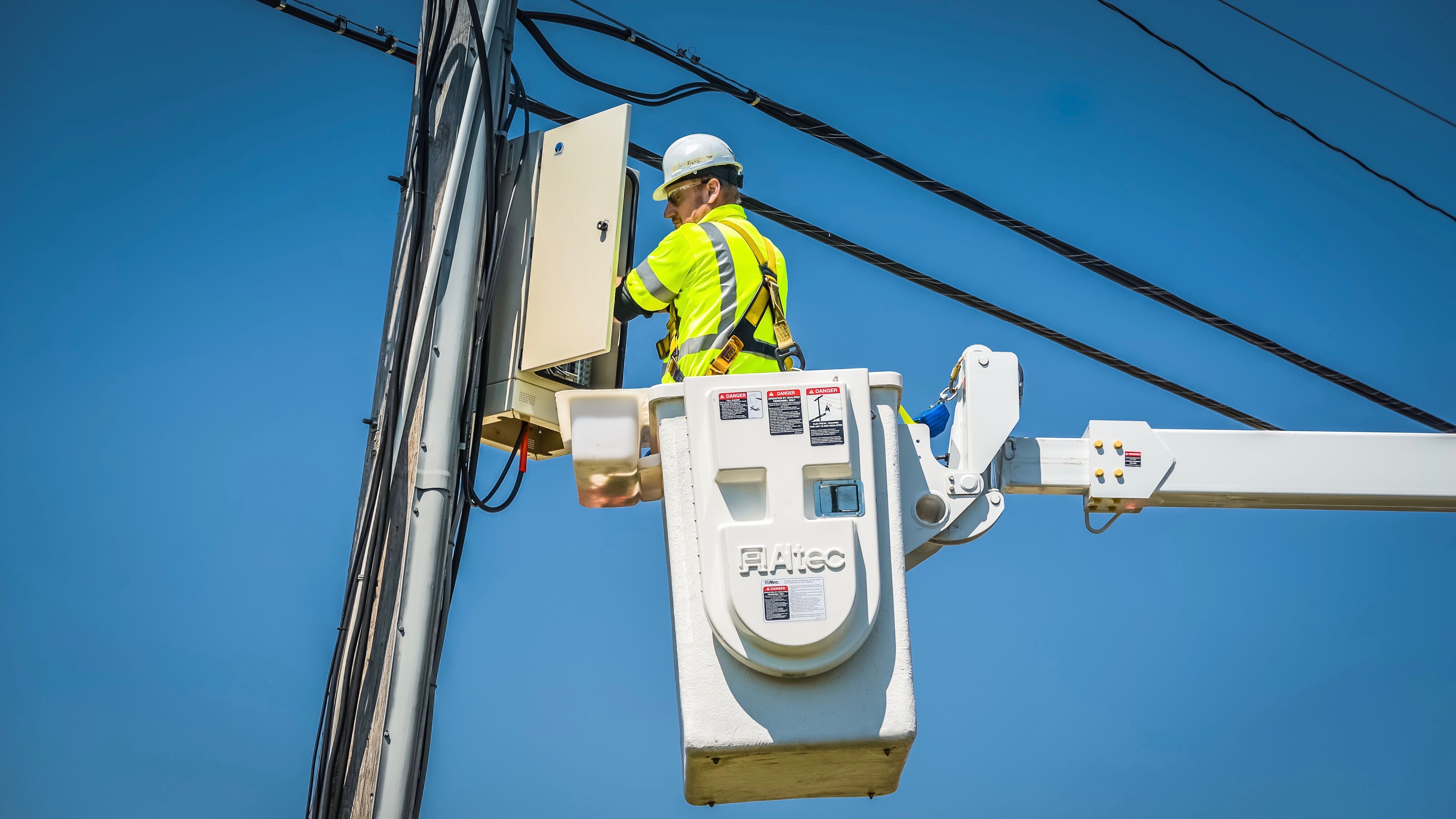 An Xfinity technician repairs equipment on a telephone pole.