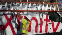 An Xfinity technician removes a ladder from an Xfinty van.