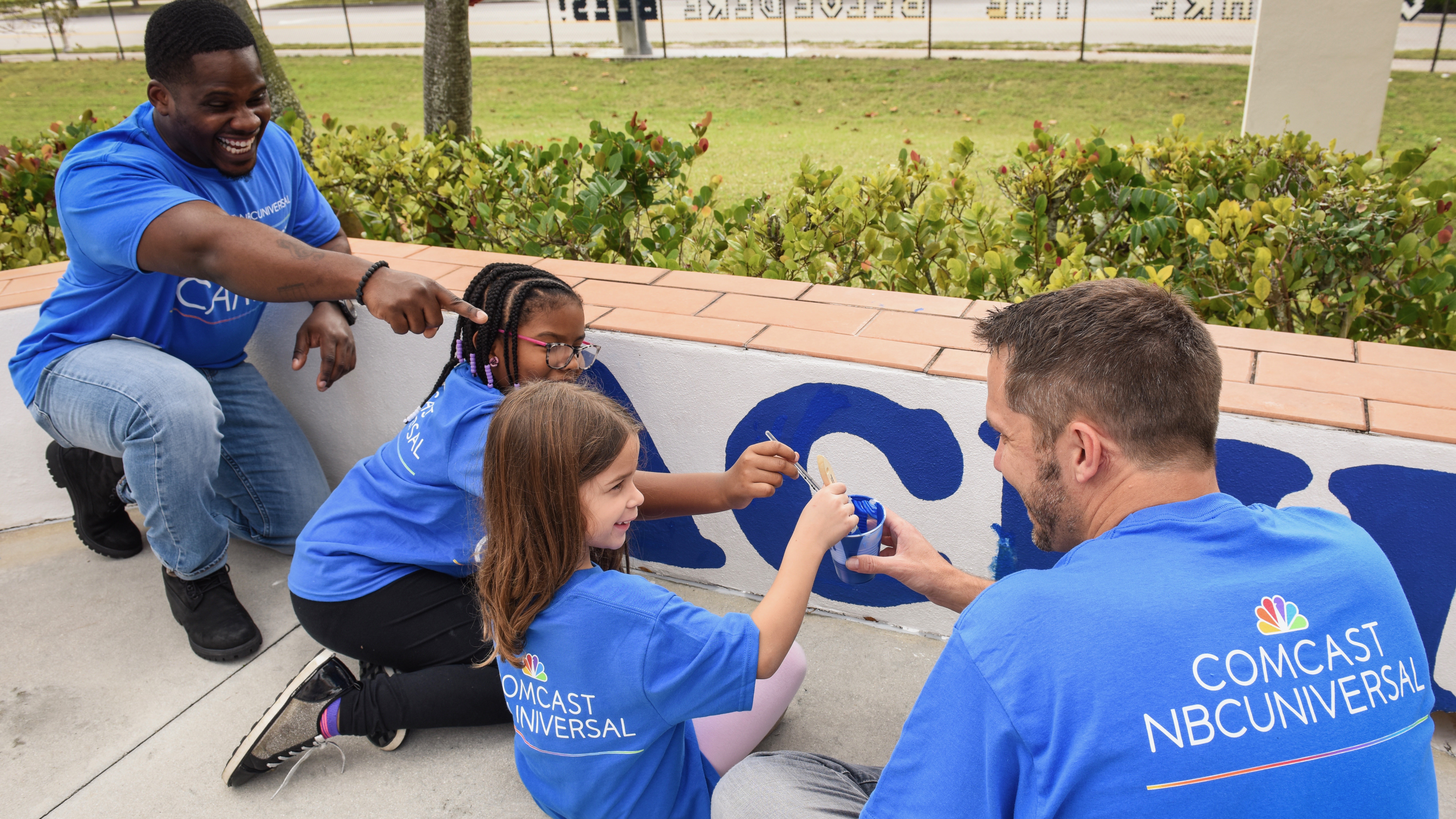 Comcast Cares Day volunteers paint a wall.