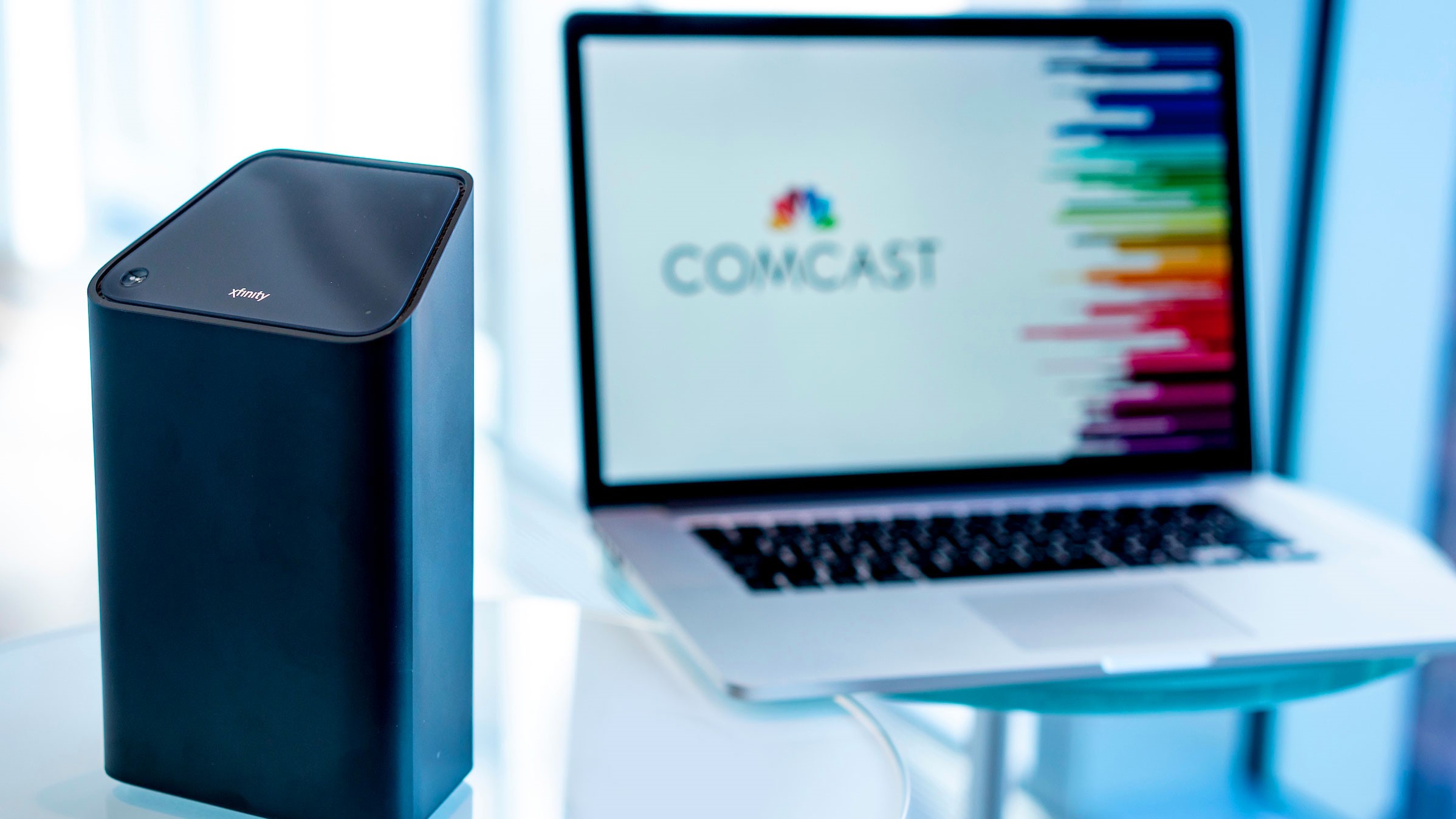 An Xfinity xFi Advanced Gateway and a laptop displaying the Comcast logo