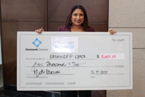 A Comcast Business and the Gwinnett Chamber of Commerce grant recipient holding a giant check.