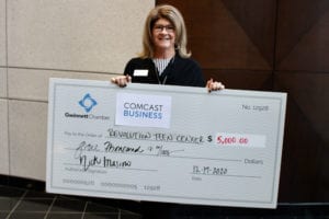 A Comcast Business and the Gwinnett Chamber of Commerce grant recipient holding a giant check.