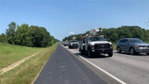 Several Xfinity work trucks driving on a highway.