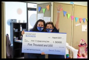 Two women hold an oversized check