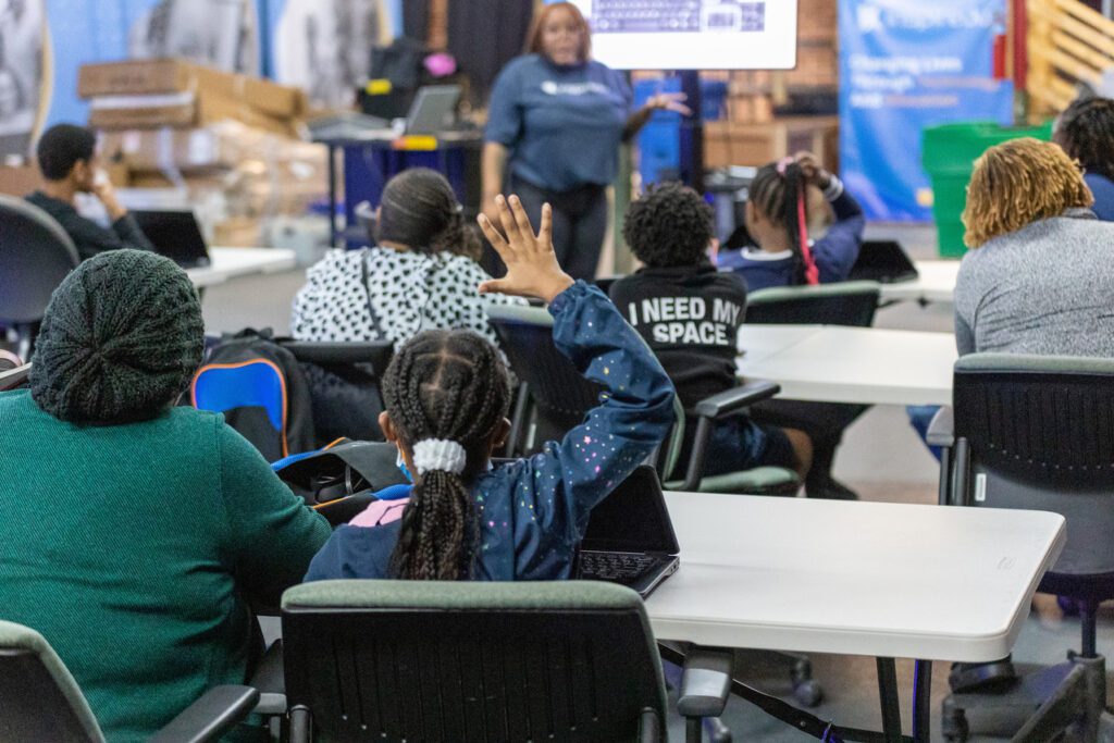 Child raises hand in a classroom type setting.