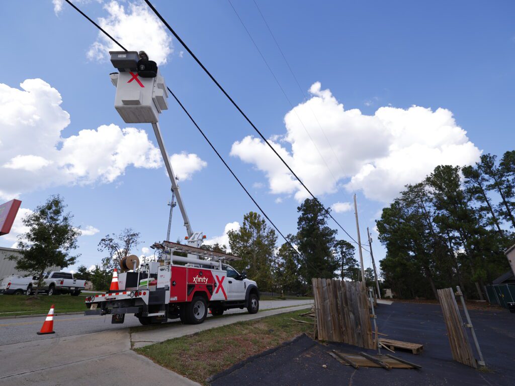 Comcast technicians in bucket trucks work to repair damage